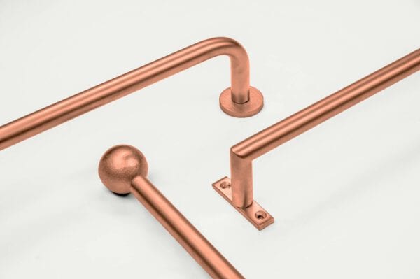 Three copper-colored metal rods are displayed against a light background. One rod features a round end, while the others have right-angle bends.