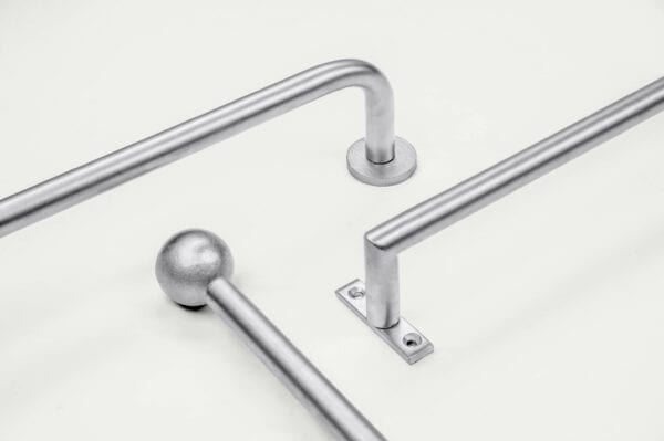 Three silver metal rods with different angles and fittings lie on a plain white background.