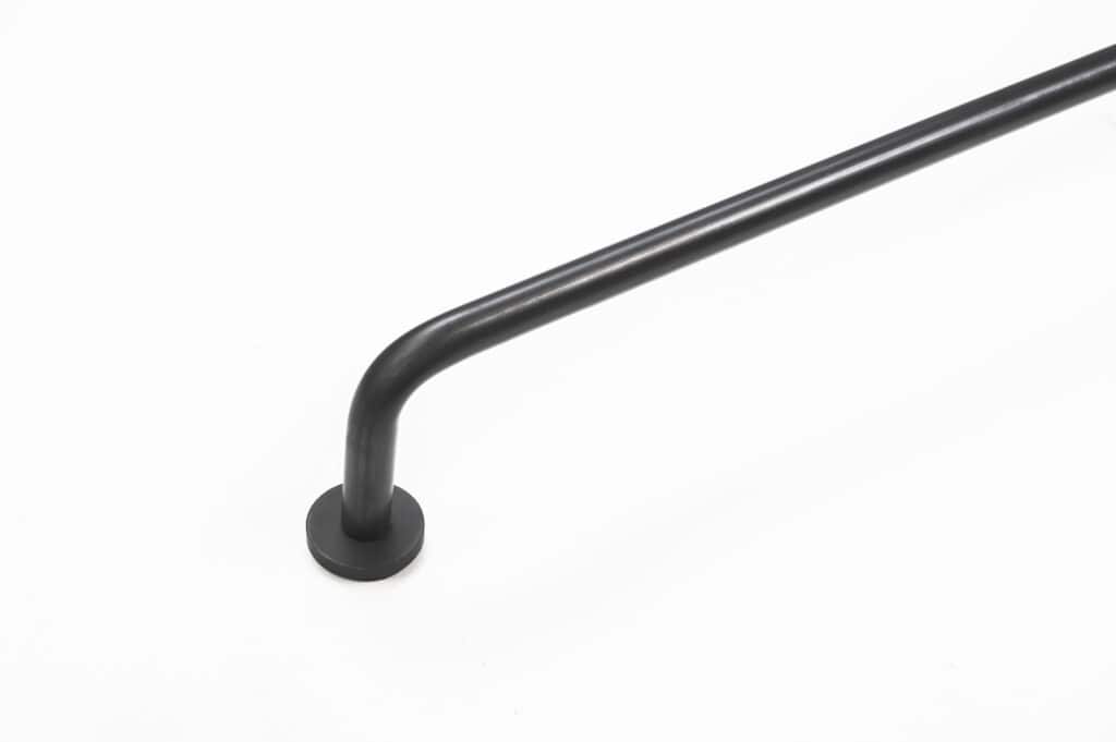 Black metal rail or handlebar mounted on a wall against a white background.