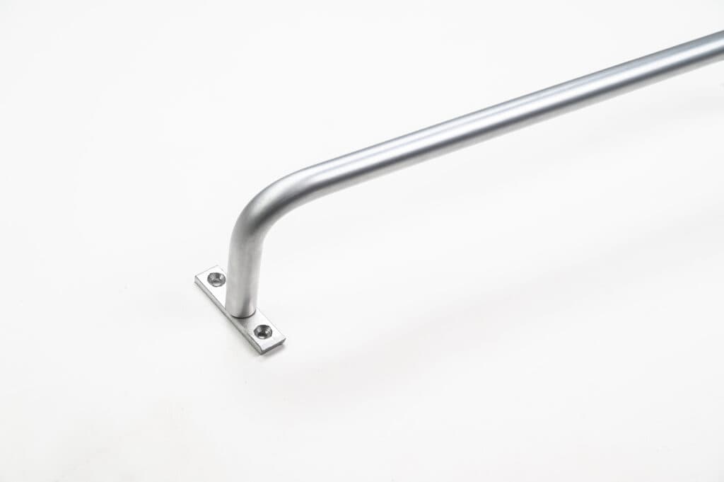 Stainless steel grab bar mounted on a white wall, with two visible screws on the mounting plate.