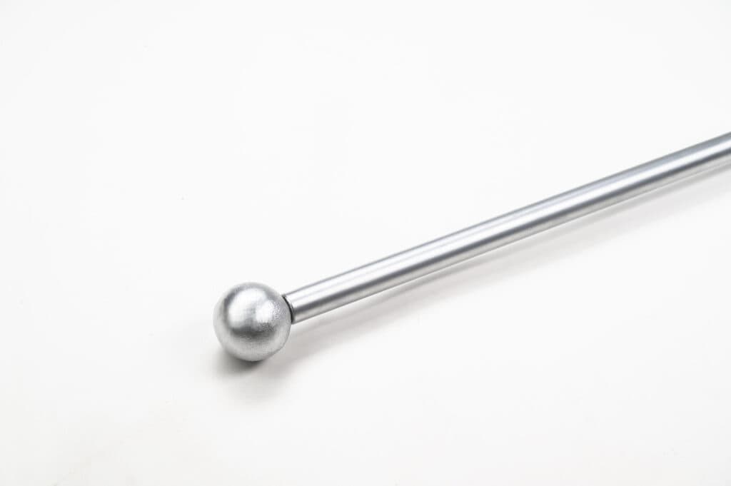 A silver metal rod with a rounded end placed diagonally on a white background.