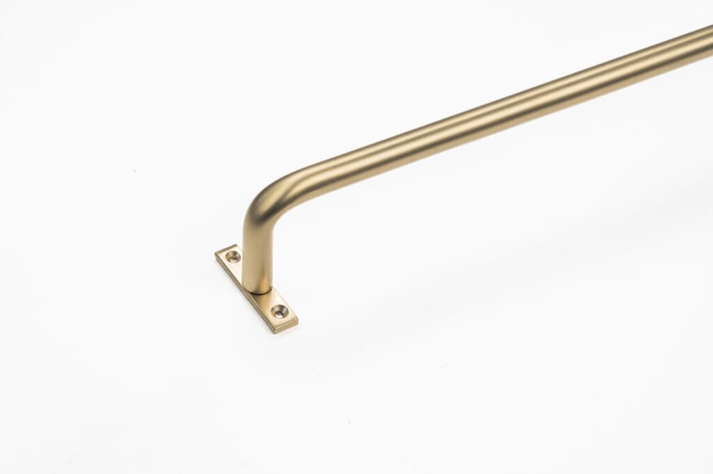 A gold-colored metal rail, resembling a curtain rod, features a right-angle bend and mounts on a rectangular base with two screws against a white background.