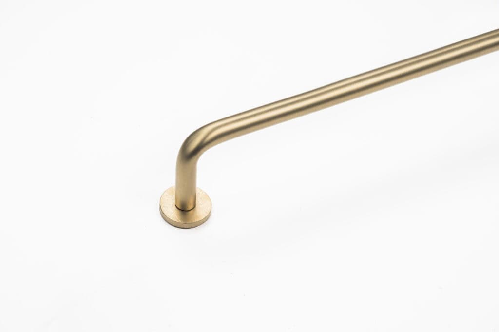 A gold metal handrail with a sleek, curved design is mounted on a plain white background.