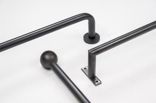 Three black metal bars on a white surface. One has a round end, and the other two have right angles with flat mounting bases.