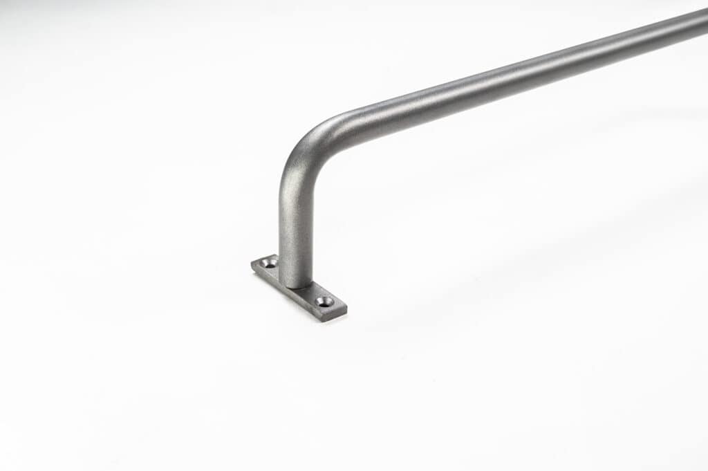 A metal handrail with a right-angle bend, mounted to a flat surface with a rectangular base plate and two visible screws.